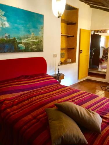 a bedroom with a red bed with a painting on the wall at Borgo Vecchio in Carbognano