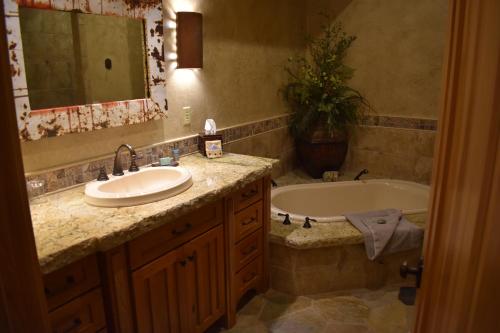 a bathroom with a sink and a tub and a mirror at Cougar Ridge Resort in Torrey