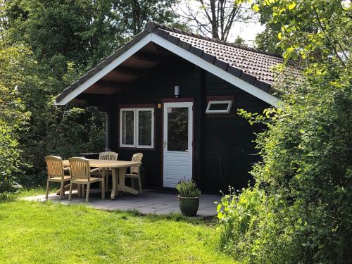 a black shed with a table and chairs on a patio at Vakantiehuisjes Robersum in Vierhuizen