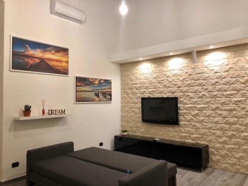 ein Wohnzimmer mit einem Sofa und einem TV an einer Backsteinwand in der Unterkunft Corte Del Carmine in Bari