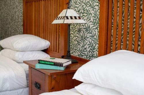 a table with books and a lamp on a table between two beds at Athenaeum Hotel in Chautauqua