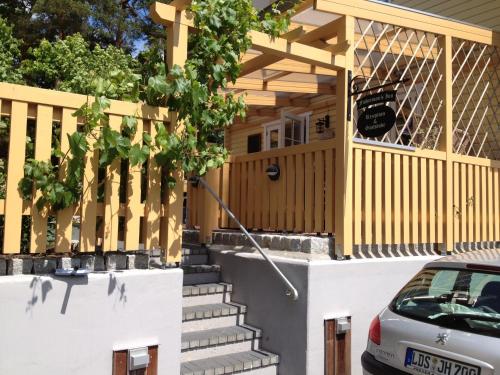 a wooden house with stairs and a car parked in front at Haus Stoertebeker Appartements - Hotel Garni, Seebad Lubmin in Lubmin