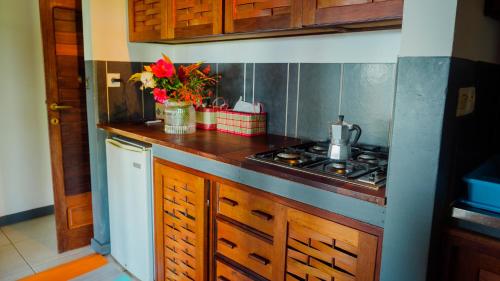a kitchen with a counter with a stove and flowers at MADIROKELY HOUSE Nosy Be in Ambatoloaka