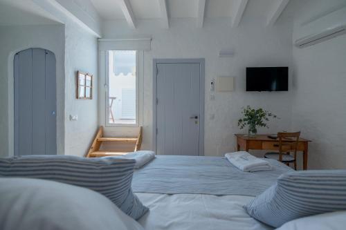 a white bedroom with two beds and a television at HOTEL ANHEL in Ferreries