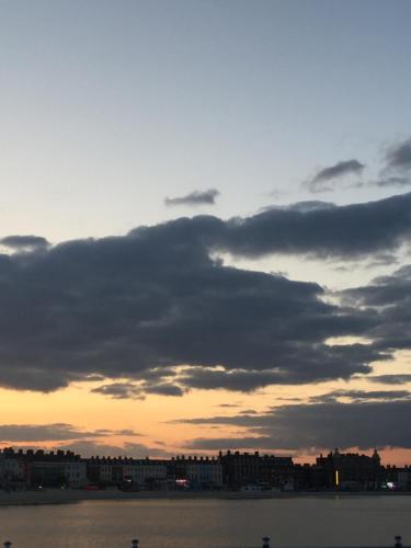 a cloudy sky over the water with a city at The Ocean Guest House in Weymouth