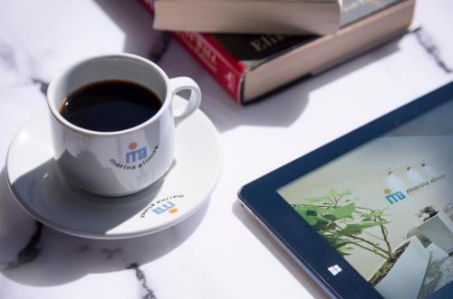 a cup of coffee on a plate next to a book at Marina Alimos Hotel Apartments in Athens