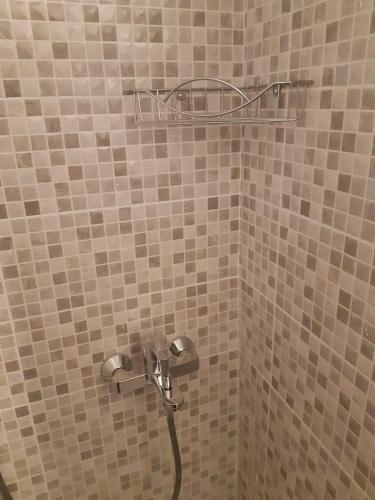a shower with a hose in a tiled bathroom at Apartments Vukelić in Starigrad