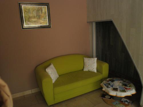 a green couch in a living room with a table at gîte le voyageur in Tours-en-Vimeu