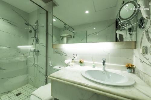 a white bathroom with a sink and a shower at LeChateau Boutique Hotel in Jeddah