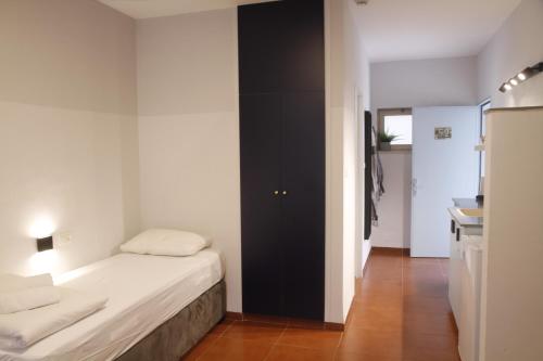 a small bedroom with a bed and a black door at Bait Alfa Kibbutz Country Lodging in Bet Alfa