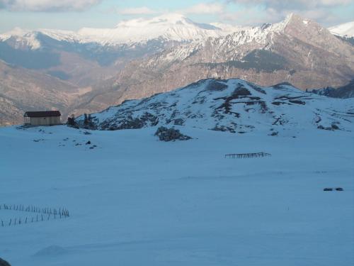 a snow covered mountain with a building in the foreground at Xenonas Kypseli in Kipseli