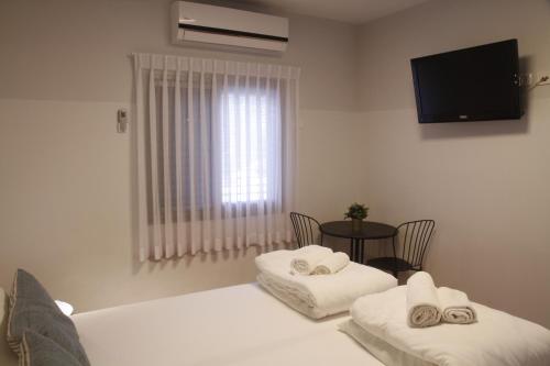 a room with two beds and a table and a television at Bait Alfa Kibbutz Country Lodging in Bet Alfa