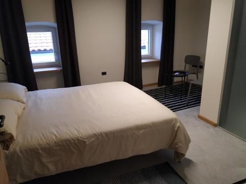a bedroom with a white bed and two windows at B & W KRIŽ in Ajdovščina