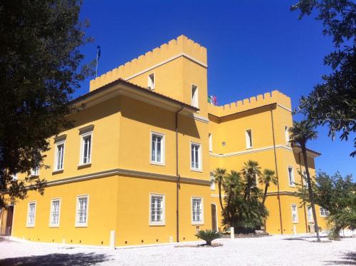 un gran edificio amarillo con árboles delante de él en Villa Graziani, en Vada