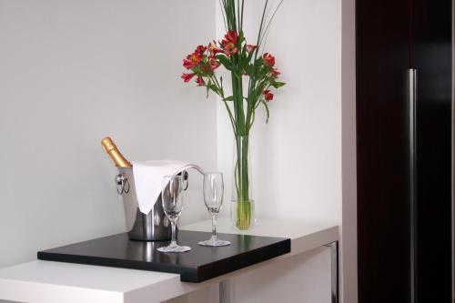 a vase with flowers and wine glasses on a counter at San Isidro Plaza Hotel in San Isidro