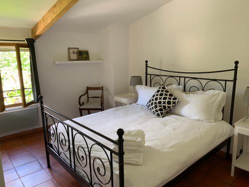 - une chambre avec un lit noir et des oreillers blancs dans l'établissement Maison Moutas, au Thoronet
