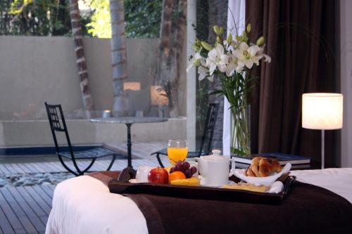 a tray of food with fruit and orange juice on a bed at San Isidro Plaza Hotel in San Isidro