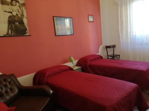 two beds in a room with red walls at casa vacanze Toto e Nina in Aradeo
