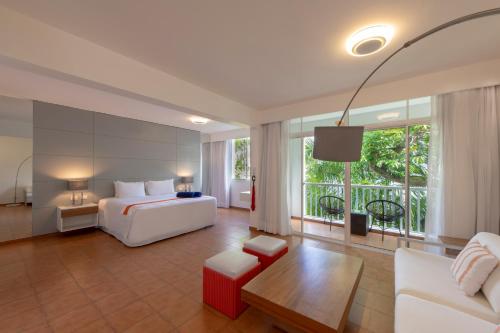 a hotel room with a bed and a couch and a tv at Viva Heavens by Wyndham, A Trademark All Inclusive in San Felipe de Puerto Plata