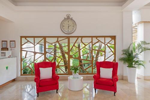 two red chairs in a living room with a clock at Viva Heavens by Wyndham, A Trademark All Inclusive in San Felipe de Puerto Plata