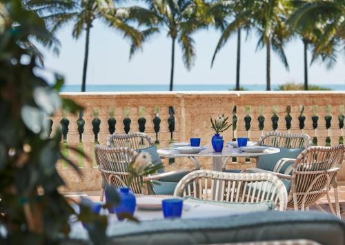 a patio with tables and chairs with palm trees in the background at Four Seasons Hotel at The Surf Club in Miami Beach