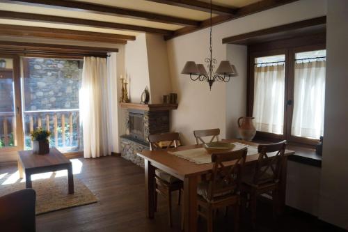 Acogedora casita en el Pallars في Isil: غرفة طعام مع طاولة وكراسي ومدفأة