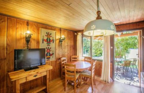 a dining room with a television and a table with chairs at Cabañas Mapulay in Pucón