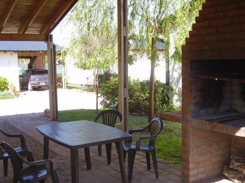 un patio con mesa, sillas y chimenea en Cabañas Don Mario en Sierra de la Ventana