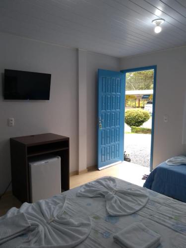a bedroom with a bed and a television and a door at Pousada Recanto Alpino in Gramado