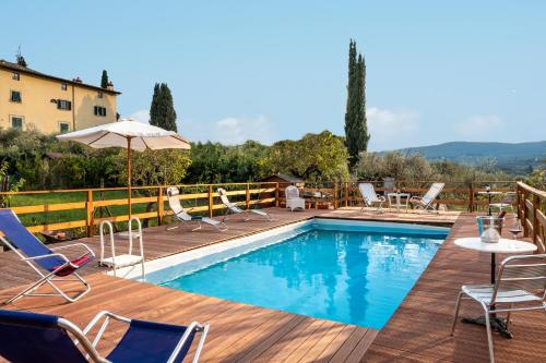 een zwembad met stoelen en een parasol op een houten terras bij La Capannaccia in Scandicci