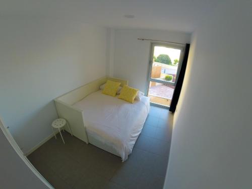 um pequeno quarto com uma cama branca e almofadas amarelas em Casa Bonita Médano em El Médano