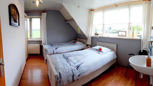 two beds in a room with a sink and window at B&B Veluwemeerpension in Nunspeet