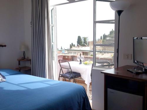 a bedroom with a bed and a balcony with a table at Bed and Breakfast Sorriso in Taormina