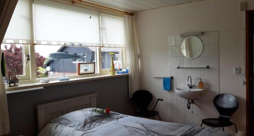 a bedroom with a bed and a sink and a window at B&B Veluwemeerpension in Nunspeet