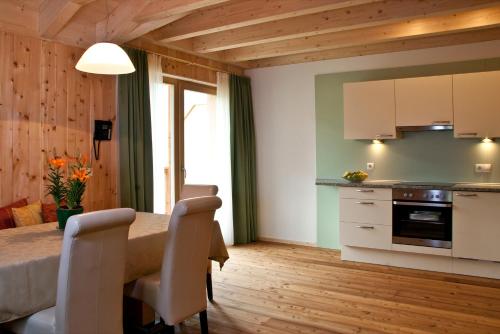 a kitchen and dining room with a table and chairs at Appartments Helvetia in Villabassa