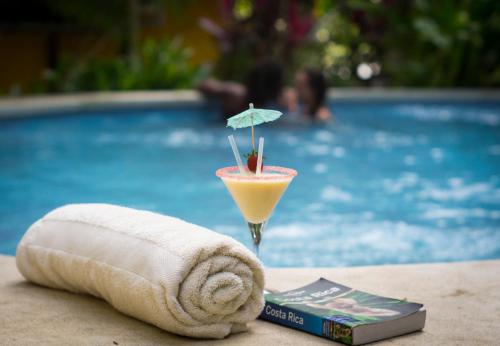 a drink sitting on a table next to a swimming pool at Pura Vida Mini Hostel Santa Teresa in Santa Teresa Beach