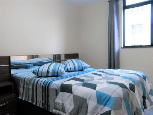 een slaapkamer met een bed met een blauw en wit dekbed bij Excelente Apto Próx. Centro Curitiba in Curitiba
