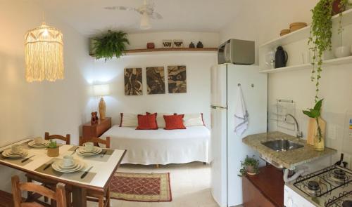 a room with a bed and a table and a kitchen at Estúdio Sabiá in Florianópolis