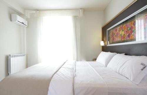 a white bed in a room with a window at Plaza Paradiso Petit Hotel in Chacras de Coria