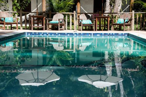 ein Swimmingpool mit Stühlen und Liegen im Wasser in der Unterkunft Cheiro Nativo - Chalés & Pousada in Trancoso