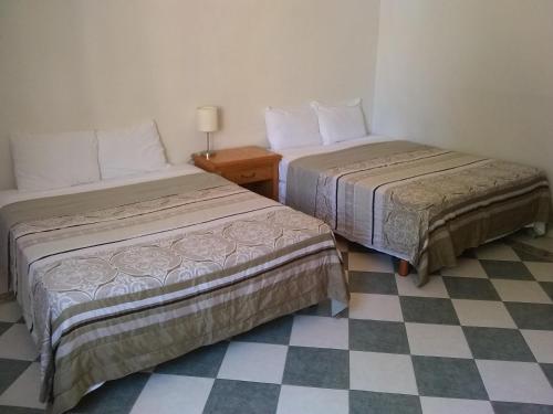 two beds in a room with a checkered floor at Yucatan Vista Inn Guest House in Mérida