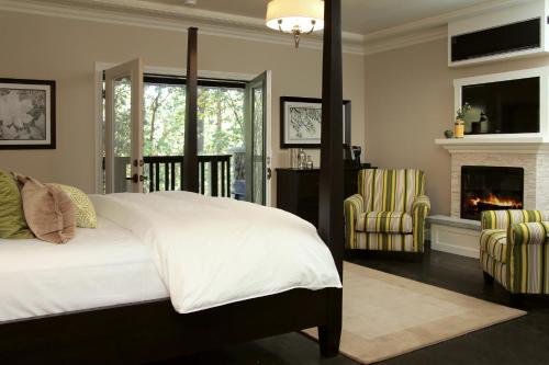 a bedroom with a bed and two chairs and a fireplace at The Grand Idyllwild Lodge in Idyllwild