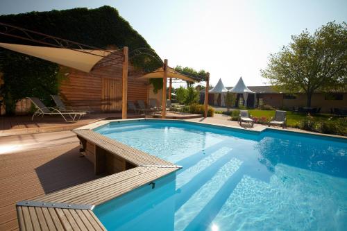 une grande piscine avec une terrasse et un parasol dans l'établissement Valsoyo, à Upie