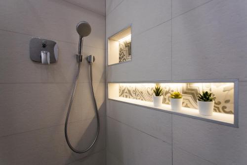 uma casa de banho com um chuveiro com luzes e vasos de plantas em Relax Apartment em Split