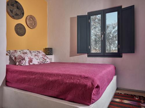 a bedroom with a red bed with a window at Koufonisi Villas in Koufonisia