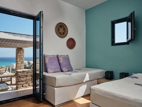two beds in a room with a view of the ocean at Koufonisi Villas in Koufonisia
