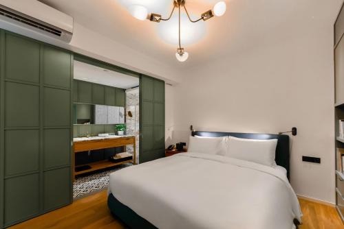 a bedroom with a white bed and a green cabinet at Hotel Kapok Shenzhen HouHai (Close to Shenzhen Bay) in Shenzhen