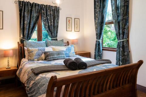 a bedroom with a bed with blue curtains and a window at Sidneys Retreat in Katoomba