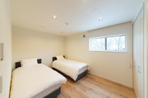 a bedroom with two beds and a window at Black Crane Chalet by Hakuba White Fox Company in Hakuba