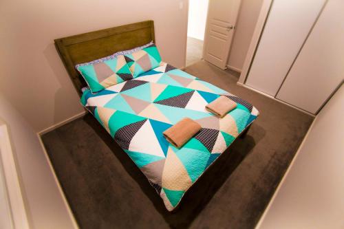 ein Schlafzimmer mit einem Bett mit einer bunten Bettdecke und Kissen in der Unterkunft Serene Shores in Wellington East
